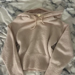 Ljusrosa stickad hoodie från Gina Tricot - Mysig ljusrosa hoodie från Gina Tricot i stickat material. Tröjan har huva med snörning, ribbade muddar och långärmad passform. Perfekt för dig som gillar en chill och soft stil. Snygg att matcha med jeans eller leggings. Passar om du är S