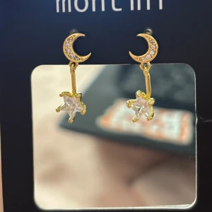 Guldiga örhängen med måne och stjärna - Supersöta örhängen i guldton med små gnistrande månar och hängande stjärnor i klar sten. 