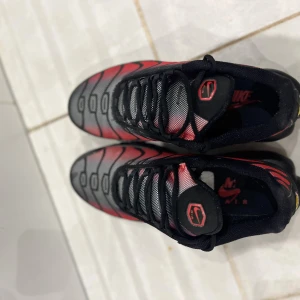 Nike TN röd svarta - Nike TN Röd Svarta  Snygga och ikoniska Nike TN i röd/svart färgkombination. Bekväma, snygg passform och riktigt bra skick! Perfekta för dig som gillar streetwear och vill sticka ut lite extra. 