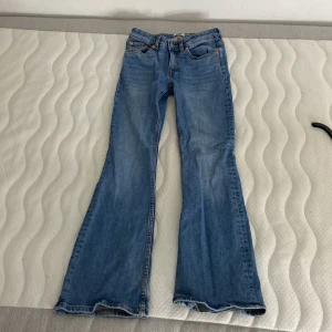Blå bootcut jeans 157 XS short - Snygga blå Lågmidjade bootcut jeans från 157 i storlek XS short. Jeansen har låg midja och klassisk femficksdesign. Tillverkade i mjukt denim med lätt utsvängda ben för en trendig siluett. Perfekta för dig som gillar retrovibbar och vill ha ett par jeans som sticker ut.
