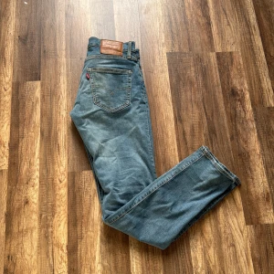 Levi's 511 blå jeans  - Säljer ett par klassiska Levi's 511 jeans i blå denim. Modellen är slim fit med normal midja och raka ben. Jeansen har fem fickor, snygga slitningar och den ikoniska läderpatchen bak i midjan. Perfekta för en avslappnad och stilren look. Är i helt utmärkt skick och har inga tecken så slitage