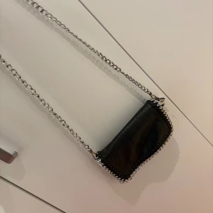 Tiamo Väska - Säljer en snygg Tiamo väska i färgen svart. Väskan är fått lite missfärgning på kedjan men det är inget som syns annars så är väskan i fint skick.🖤