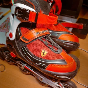 Röda Ferrari inlines rullskridskor stl. 38-41  - Snygga inlines med Ferrari Scuderia-design i rött, svart och vitt. Skorna har mesh- och syntetmaterial, robusta spännen, snörning och italienska flaggdetaljer. ABEC-7 kullager för smidig åkning. Perfekta för dig som vill sticka ut med sportig stil.