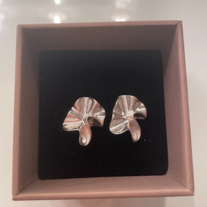 Silvriga örhängen med organisk form - Unika silvriga örhängen med en cool, organisk och böljande form som påminner om blad eller abstrakt konst. Perfekta för dig som gillar statement-smycken med modern vibe. 