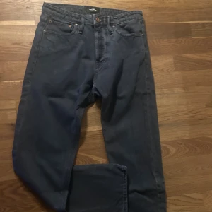 Mörkblå jeans från Jack & Jones - Snygga mörkblå jeans från Jack & Jones med klassisk femficksdesign och bruna metallknappar. Jeansen har rak passform och är tillverkade i slitstarkt bomullsmaterial. Perfekt för dig som gillar en enkel och stilren look. Pris går att diskutera vid snabb affär!