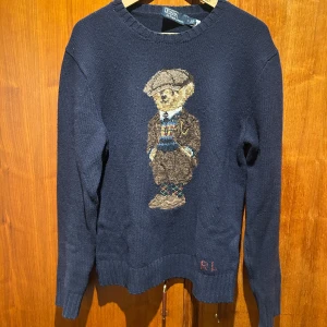 Mörkblå stickad tröja Polo Bear - Ralph lauren tröja som är köpt på Ralph Laurens flag shop i London i somras för ca 7 tusen kr. Oerhört fin kvalité och näst intill nyskick på denna. Det ända är att lappen i bak har lossnat lite vilket var mitt fel… utöver det skulle jag säga att den är fläck fri.