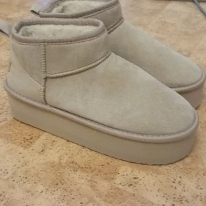 Beige plattform boots i mocka - Säljer ett par beige boots med plattformsula och rund tå. Skorna är fodrade med mjukt foder och har ett yttre i mocka. Perfekta för kalla dagar och ger en trendig look med sin chunky sula och neutrala färg.