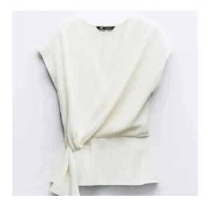 Vit omlottopp med knyt från Zara - Säljer en stilren vit omlottopp från Zara i storlek XS. Toppen har korta ärmar, v-ringning och snygg knytning i sidan som ger en modern look💗💓💗💓
