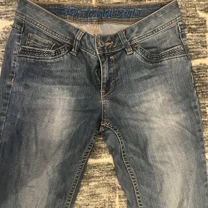 Blå jeans från Esprit med detaljer - Snygga blå jeans från Esprit med slitningar och kontrastsömmar. Klassisk femficksmodell med dekorativa sömmar på fickorna och läderpatch bak. Dragkedja och knapp framtill. Perfekta för dig som gillar en avslappnad denimlook.