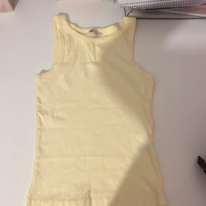 Ljusgul ribbad linnetopp XS - Supersöt ljusgul ribbad linnetopp från C i storlek XS. Toppen är ärmlös och har en klassisk rak skärning, perfekt till varma dagar. Mjuk och stretchig känsla i materialet som gör den riktigt bekväm att bära.