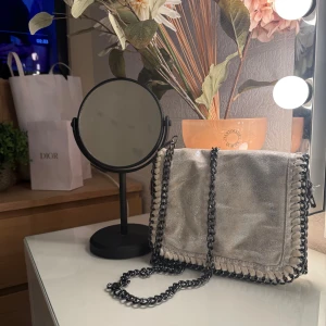 Stella McCartney liknade väska - Snygg axelväska med grov svart kedja som axelrem. 🥰Väskan har ett lock med magnetknapp, dekorativa sömmar längs kanterna och ett innerfack med dragkedja. 😍Perfekt för dig som vill sticka ut med en cool accessoar. Har även en extra kedja som man ser på bild 3, om man vill göra den ännu längre!❤️