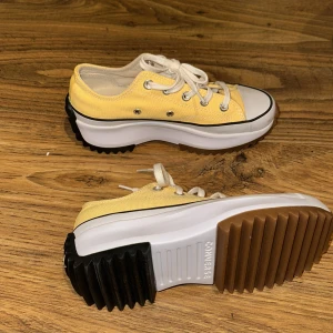 Gula Converse Run Star Hike sneakers - Säljer ett par Converse Run Star Hike sneakers i en fräsch gul färg med vit tå och kraftig, räfflad sula i vitt, svart och brunt. Skorna har snörning, canvasmaterial och den klassiska stjärnan baktill. Perfekta för dig som vill sticka ut med din stil. Dem här skorna är helt nya