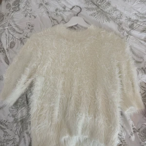 Vit fluffig stickad tröja Carin Wester - Supermjuk och fluffig vit stickad tröja från Carin Wester. Tröjan har trekvarts ärm och en riktigt cozy känsla med sitt lurviga material. Perfekt för dig som vill ha en mysig och trendig look under kyliga dagar.