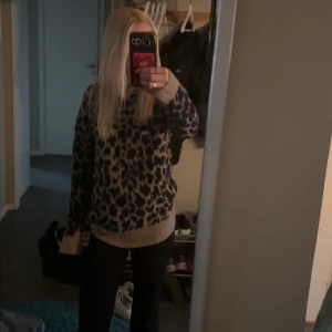 Leopardmönstrad stickad tröja - Säljer en oversized stickad tröja med leopardmönster i mörkblått och beige. Tröjan har breda ribbade muddar vid ärmslut och nederkant samt lång ärm. Perfekt för dig som vill sticka ut med en cool och trendig look.