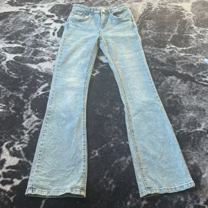 Ljusblå bootcut jeans från Denim Day - Snygga ljusblå jeans från Denim Day i klassisk bootcut-modell. Jeansen har fem fickor, normalhög midja och är tillverkade i mjukt denimtyg. Perfekta för dig som gillar en retroinspirerad look med utsvängda ben.