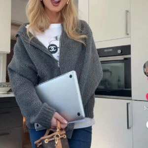 Grå stickad hoodie med dragkedja - Mysig grå stickad hoodie med huva och dragkedja framtill. Tröjan har ribbade muddar och en relaxed, lite oversized passform. Perfekt att slänga på sig över en t-shirt för en chill look.