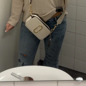 Blå slitna bootcut jeans från H&M - Säljer ett par blå jeans från H&M med snygga slitningar. Jeansen är bootcut och jätte lågmidjad. Storlek 36/S