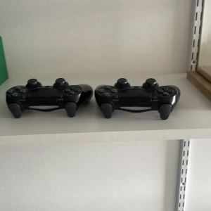 PlayStation DualShock 4 kontroll - Två svarta Sony DualShock 4 kontroller till PlayStation 4 i gott skick. Alla knappar och spakar är hela ut, inga synliga repor eller skador. Perfekt för extra spelare eller som ersättningskontroller.