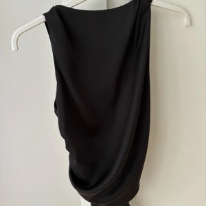 Svart omlottopp med knyt i ryggen - Supersnygg festtopp från zara som knyts i ryggen. Använd en gång och har inga tecken på användning! Hör av dig vid interesse!❤️