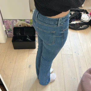 Blå utsvängda jeans från Zara - Snygga blå jeans från Zara med klassisk femficksdesign och utsvängda ben. Jeansen har normalhög midja och är tillverkade i mjukt denimtyg med lite stretch för skön passform. Perfekta till sneakers eller boots för en avslappnad look.