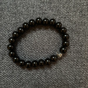 Svart pärlarmband med silverdetalj - Stilrent armband med svarta runda pärlor och en liten silverfärgad rosdetalj. Perfekt accessoar för att lyfta din outfit med en enkel men cool touch.