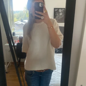 Vit stickad tröja med kort ärm - Säljer en enkel och stilren vit stickad tröja med korta ärmar. Tröjan har en rak passform och rund halsringning, perfekt att matcha med jeans eller kjol. Mjuk och skön att bära, passar till många olika tillfällen. Den är ifrån Gina tricot.