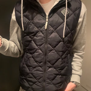 Sällsynt och exklusiv Gant väst! - Snygg quiltad väst från Gant. Västen säljs inte längre och är alltså väldigt exklusiv och sällsynt. Den är helt oanvänd. Den har inga märken, defekter eller hål. Skick: 10/10, Storlek: 180cm/ 18 år. Men är stor i storleken och skulle kunna säga M i herrstorlek. Vid önskemål av mått på västen eller tydligare bilder är det bara att höra av sig! Priset kan diskuteras vid snabb affär!