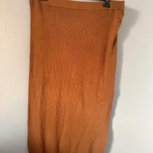 Rostbrun ribbad långkjol 2XL - Säljer en snygg rostbrun ribbad långkjol  i storlek 2XL. Kjolen har en rak passform och är tillverkad i mjukt, stickat material. Perfekt för dig som gillar en enkel men trendig look med höstiga vibes.