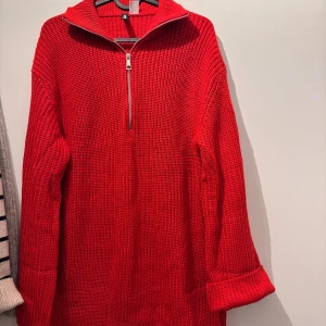 Röd stickad half zip-tröja H&M - Säljer en chunky röd stickad tröja från H&M med halv dragkedja och stor krage. Tröjan har långa ärmar med breda muddar och en loose fit som ger en chill vibe. Perfekt för lager på lager under kyliga dagar.