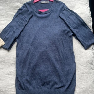 Mörkblå stickad tröja Dressmann - Mörkblå stickad tröja från Dressmann med rund hals och ribbade muddar. Tröjan är gjord i mjukt material som känns skönt mot huden. Perfekt för dig som gillar enkel och stilren design.