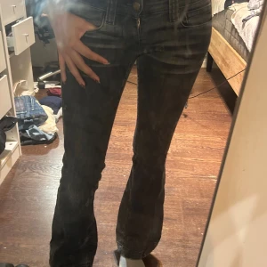 Svarta bootcut jeans med låg midja - Snygga svarta jeans med lätt tvättad look och bootcut-ben. Låg midja och klassiska femficksdetaljer. Jeansen har dragkedja och knapp framtill och är tillverkade i stretchigt denim för en bekväm passform.