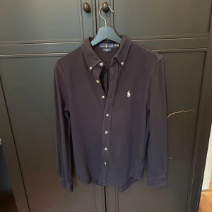 Mörkblå långärmad skjorta Ralph Lauren - Mörkblå skjorta från Ralph Laurent i festverksamhet weight mech, vilket är väldigt skönt och snyggt. Bra skick köpt på NK