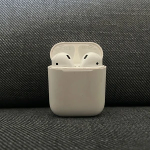 Apple AirPods (1st/2nd Gen) - Säljer mina AirPods som fortfarande funkar bra och kopplar upp som de ska. Laddningsfodralet fungerar också utan problem, hittar dock inte min box. Batteritiden är lite nedsatt. De håller ungefär 1–2 timmar per laddning, så de passar bäst för kortare användning, samtal eller som reservpar.  ✔️ Fullt fungerande hörlurar och laddningsfodral ✔️ Perfekta som budgetalternativ          ✔️ Rengjorda och klara för ny ägare  ✔️ Fulladdade nä du får dem  500 kr (Pris kan diskuteras 💞)