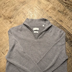 Grå merinotröja half zip These Glory Days - Snygg grå långärmad tröja från These Glory Days i mjuk merinoull. Tröjan har en stilren half zip-dragkedja vid kragen och en klassisk passform. Perfekt för lager-på-lager och funkar året runt. Enkel att matcha med jeans eller chinos. Nypris:1099