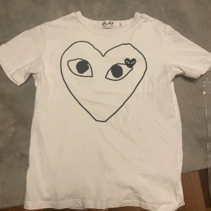 Vit Comme des Garçons Play t-shirt - Säljer denna vita t-shirt från Comme des Garçons Play, den säljes då den inte kommer till användning längre. Den är storlek L men sitter lite litet så mer åt M hållet. Tar även emot byten! Hör av dig vid minste fundering! 