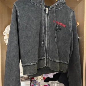 Svart hoodie från True Religion XL - Svart hoodie från True Religion i tvättad look med dragkedja framtill, huva med snörning och broderad logga på bröstet. Tjocka kontrastsömmar och croppad passform ger en cool vibe. Perfekt för dig som gillar streetwear. Passar bra för mig som har S-M vanligtvis. Nypris 1299:-. Lappen sitter kvar 😉