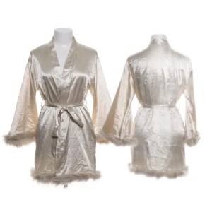 Champagnefärgad satin kimono med fuskpäls - Superfin kort kimono i champagnefärgad satin med vida ärmar och fuskpälsdetaljer vid ärmslut och nederkant. Knytband i midjan för en snygg siluett. Perfekt för dig som vill ha en lyxig och glamorös känsla hemma.