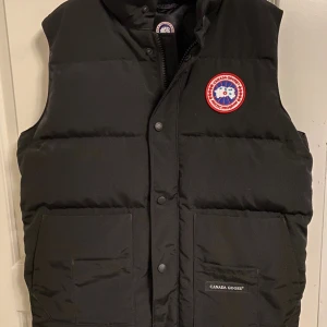 Svart dunväst från Canada Goose - Hjälper min vän att sälja hans iprincip helt nya väst, använd typ 4 gånger men legat i en garderob i ca 1 år. Finns inga skavanker på västen.