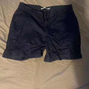 Mörkblå shorts från 157, storlek S - Snygga mörkblå shorts från 157 i klassisk modell med fickor fram och bak. De har en enkel design med midjeresår och snörning på insidan. Perfekta för varma dagar och chill häng. Materialet känns mjukt och lätt, vilket gör dem riktigt bekväma.