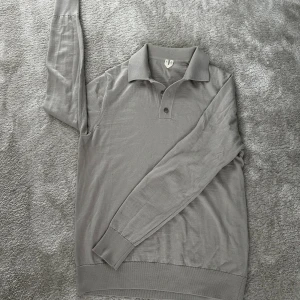 Grå/biege Tröja från arket  - Snygg 100% ull tröja med krage och 1/4 button-up. Stilren och Perfekt för vinter och höst säsongerna. Storleken är 175cm eller Small. 