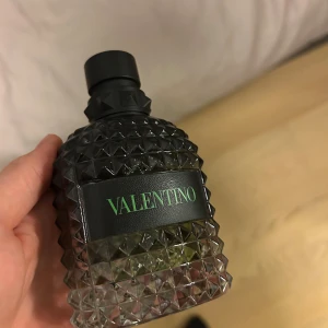 Valentino Uomo Born in Roma parfym - Stilren parfym från Valentino med cool design och grön text. Flaskan rymmer 100 ml. Perfekt för dig som vill sticka ut med en modern och trendig doftaccessoar.