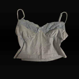 Ljusgrå linnetopp med spets och rosett. Storlek S/xs - Supersöt ljusgrå linnetopp med tunna axelband, spetsdetaljer upptill och en liten rosett framtill.  Storlek M men är absolut inte det. Passar xs och s. Bra skick och inga defekter. Skickar inom 1-2 dagar och bud tas emot!