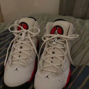  Nike Air jordan 6Y - Säljer ett par Nike Air Jordan sneakers i vitt och rött med svarta detaljer. Skorna har snörning, hög modell och klassisk Jumpman-logga på tungan och hälen. Ovandelen är i skinn och mesh för en sportig look. Perfekta för dig som gillar streetwear och basketstil🩷