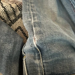 Blå jeans med klassisk passform - Säljer ett par blå jeans med klassisk rak passform och tydliga sömmar. Jeansen har en ljus tvätt och är tillverkade i robust denim. Perfekta för dig som gillar en tidlös stil och vill ha ett par jeans som funkar till det mesta.