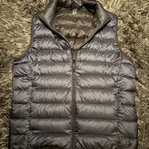 Mörkblå väst från uniqlo - Snygg mörkblå dunväst från Uniqlo i modellen Ultra Light Down. Västen är quiltad med horisontella sömmar, har hög krage och dragkedja framtill. Perfekt för lager-på-lager och enkel att bära tack vare sin lätta känsla. Har även fickor på sidorna av västen. Riktigt bra och ha nu in för hösten, hör av dig vid minsta fundering, mvh Charlie 🍁🤝(OBS kommer även med påse som du kan lägga västen i)