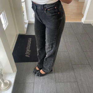 Svarta raka jeans med hög midja - Snygga svarta jeans med raka ben och hög midja. Jeansen har klassisk femficksdesign, kopparfärgade nitar och är tillverkade i ett robust denimtyg. Perfekta för dig som gillar en enkel och tidlös look.