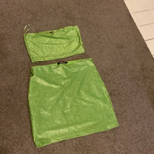 Glittrig grön kjol från Gina Tricot - Säljer en snygg glittrig grön kortkjol från Gina Tricot. Kjolen har en rak passform och är tillverkad i ett stretchigt syntetmaterial med metallicskimmer. Perfekt för dig som vill sticka ut med en färgstark look. Helt oanvänt 