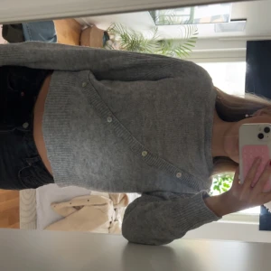 Grå stickad tröja med knappar - Supermysig grå stickad tröja med lång ärm och knappar! I mycket bra skick, säljer då den inte kommer till användning.
