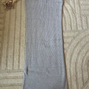 Ljusgrå ribbad långkjol - Säljer en stilren ljusgrå långkjol med ribbad struktur. Kjolen har en rak passform och är perfekt för dig som gillar en enkel och clean look. Superenkel att matcha med olika toppar och sneakers.