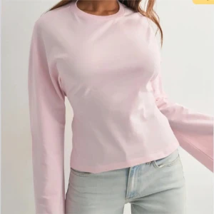 Ljusrosa långärmad tröja - Enkel och stilren ljusrosa långärmad tröja i mjukt bomullsmaterial. Tröjan har en klassisk rund halsringning och en normal passform som passar perfekt till jeans eller kjol. Perfekt för vår och sommar.